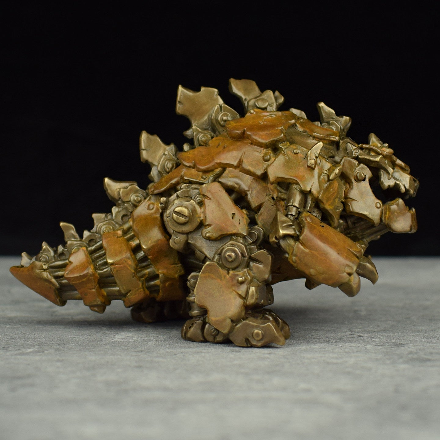 Metallic creature figurine with detailed design on a gray surface