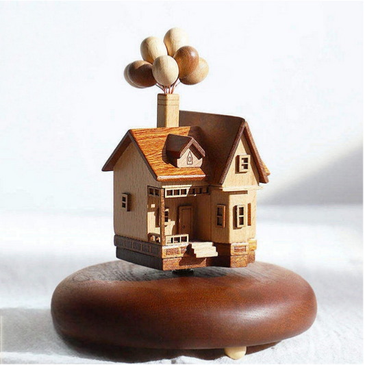 Wooden model of a house with balloons on a white background
