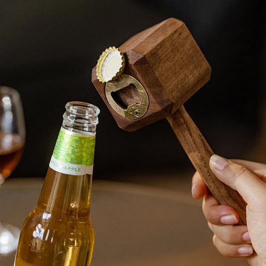 Wooden bottle opener being used on a beer bottle with a blurred background