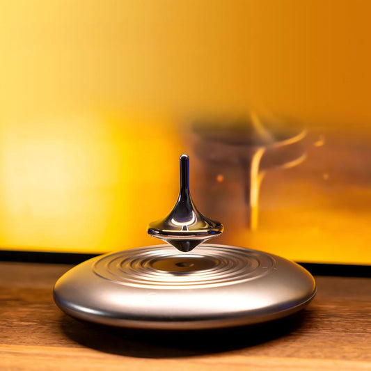 Metallic spinning top on a wooden surface with a warm yellow background