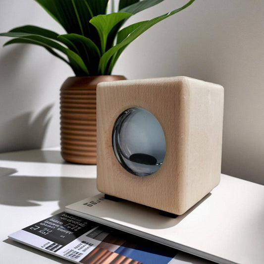 Wooden cube-shaped device on a surface with a plant in the background