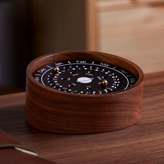 Circular walnut wood perpetual calendar with a black celestial dial and magnetic beads.