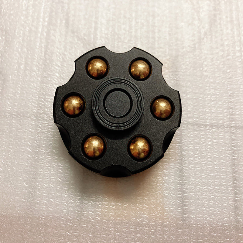 Black circular object with gold-colored beads on a white textured background