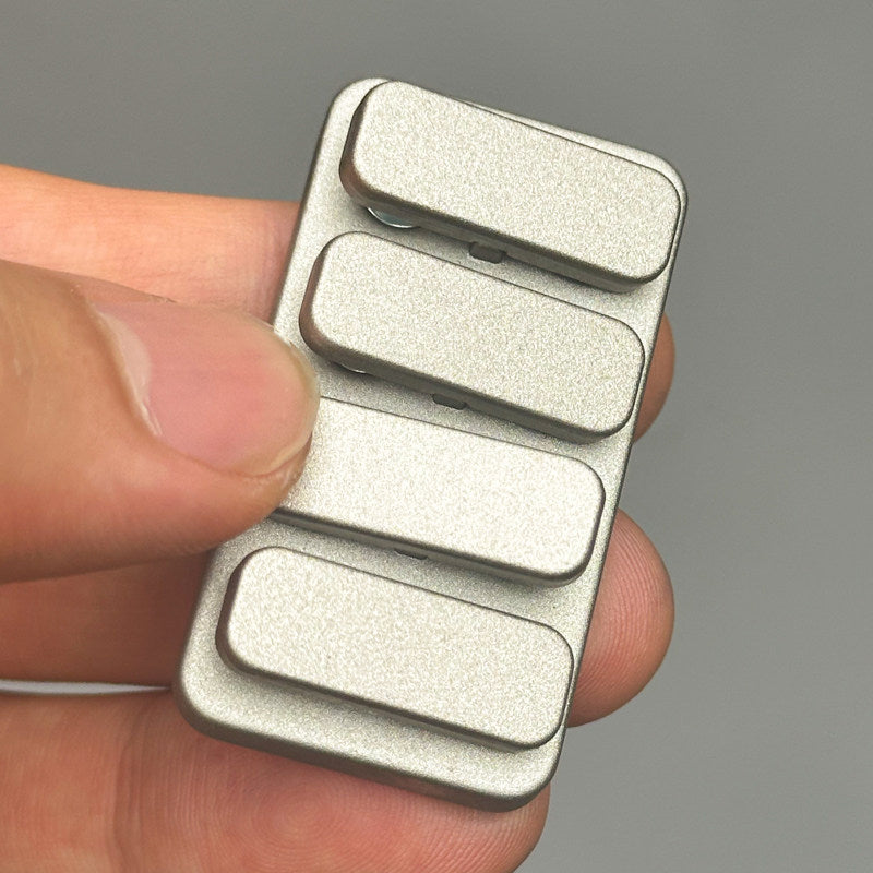 Metallic device with four rectangular buttons held in a hand against a gray background